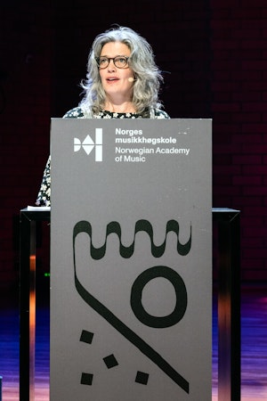 Rector Astrid Kvalbein is giving a speech at a podium.