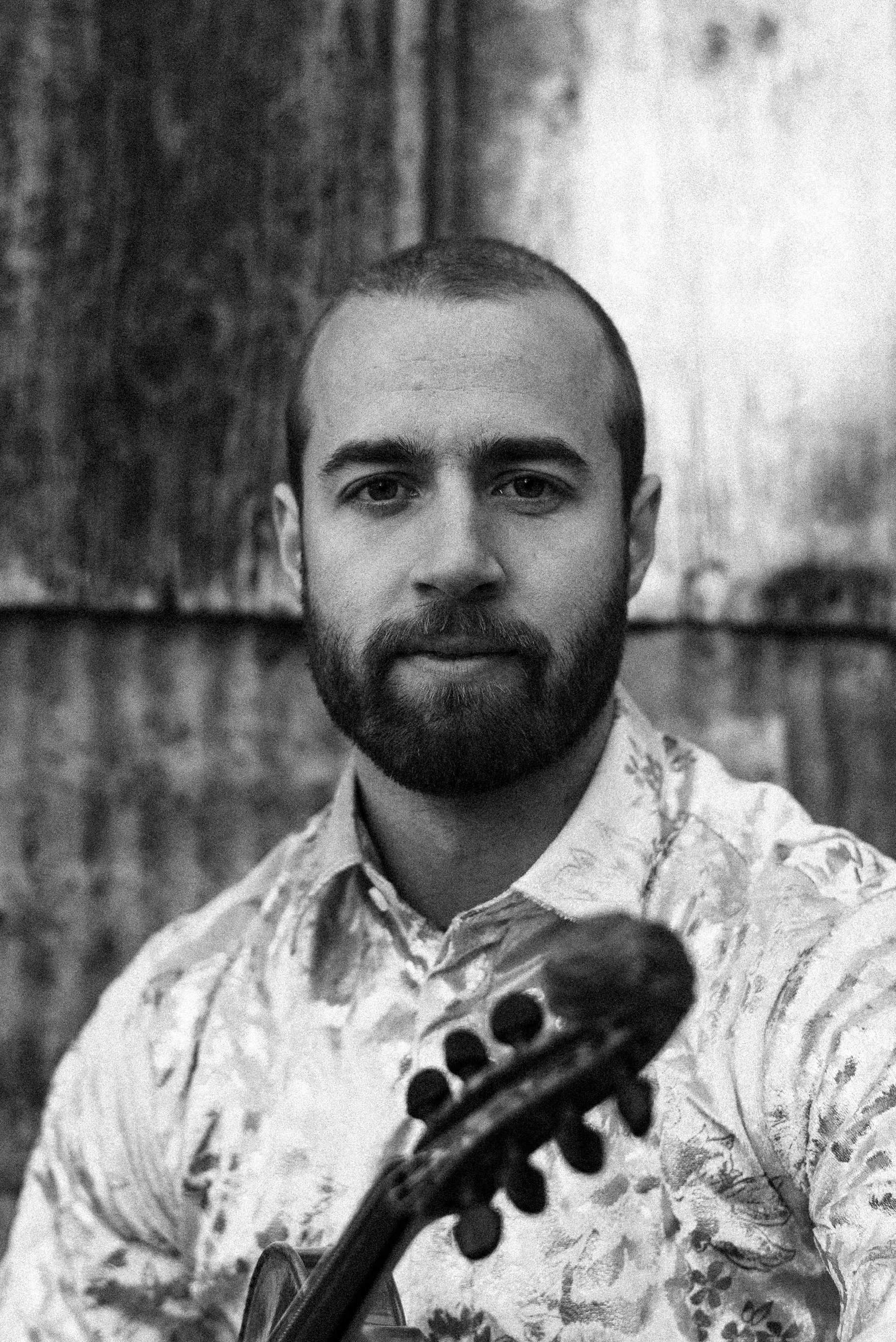 Portrett av Sivert Holmen som ser alvorlig i kamera, med fela i hånda