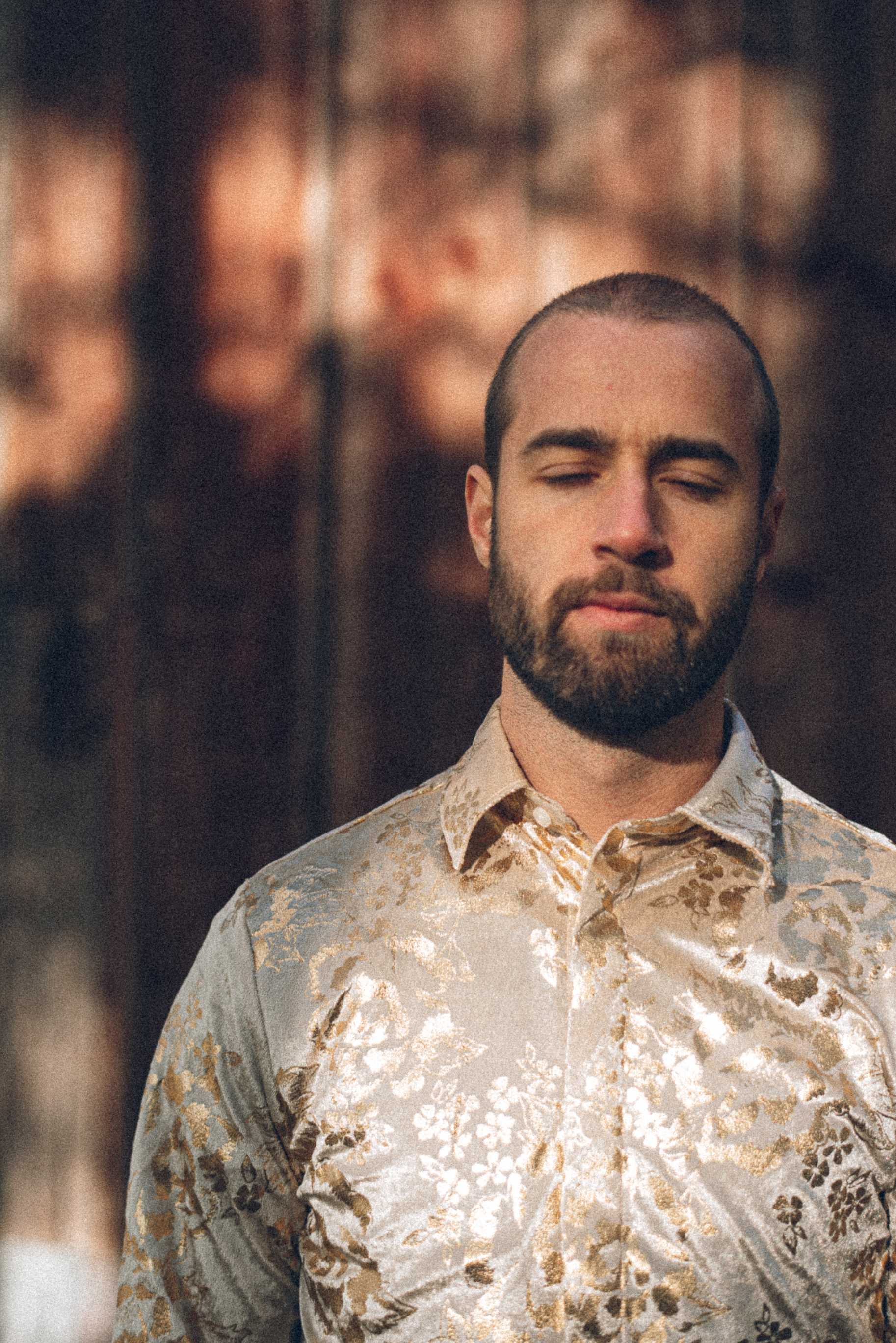 Portrett av Silvert Holmen foran en låve, med øynene lukket mot solen