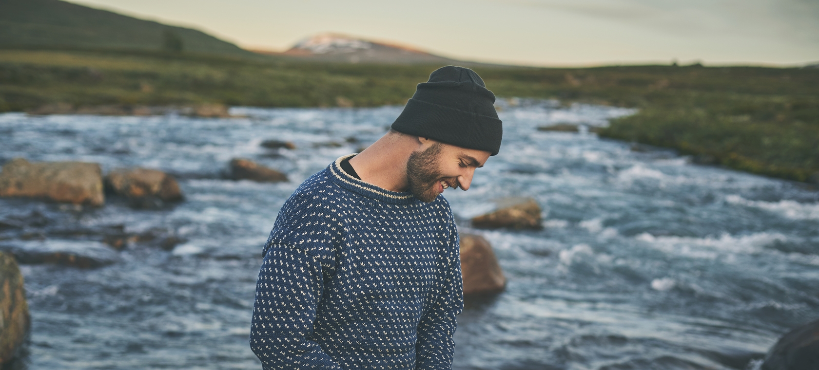 Sivert Holmen står i et vidstrakt fjell-landskap med en elv bak seg.