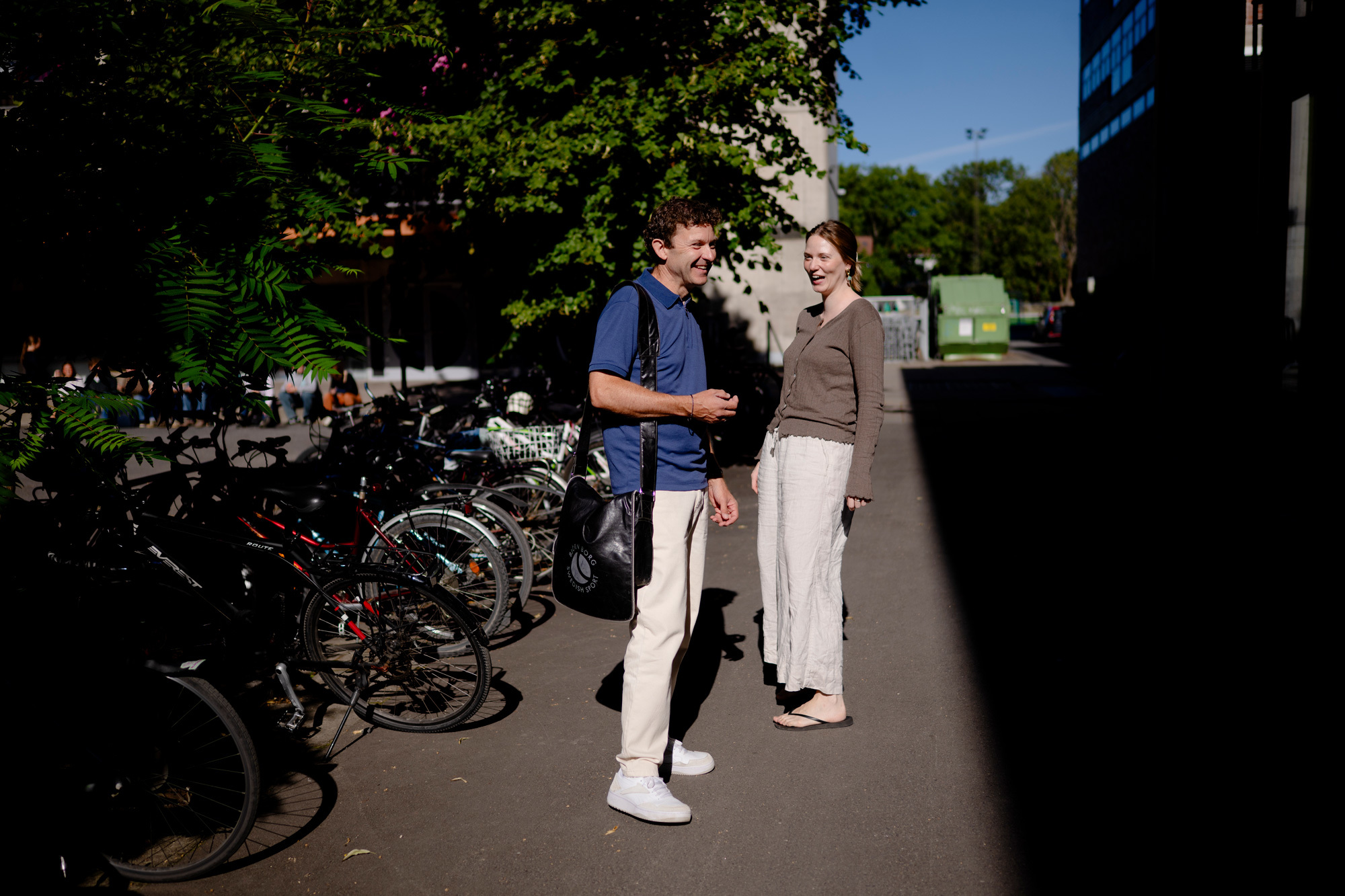 Jon Helge Sætre og Tuva Sverkeli står i skyggen av NMH foran sykkelstativ.