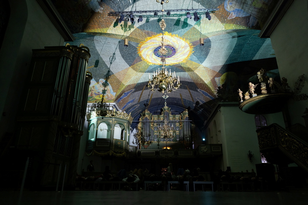Oslo domkirke, svakt opplyst i taket og ellers mørkt, med orgelet i enden.