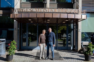 Ram Reuven og Inkeri Jaakkola står i sola foran inngangen til NMH.