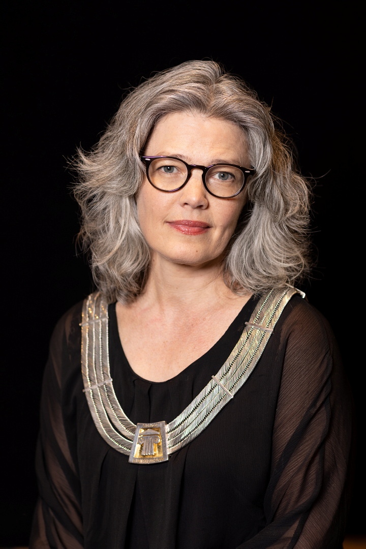 Portrett av rektor Astrid Kvalbein, med rektorkjede og et alvorlig uttrykk i ansiktet.