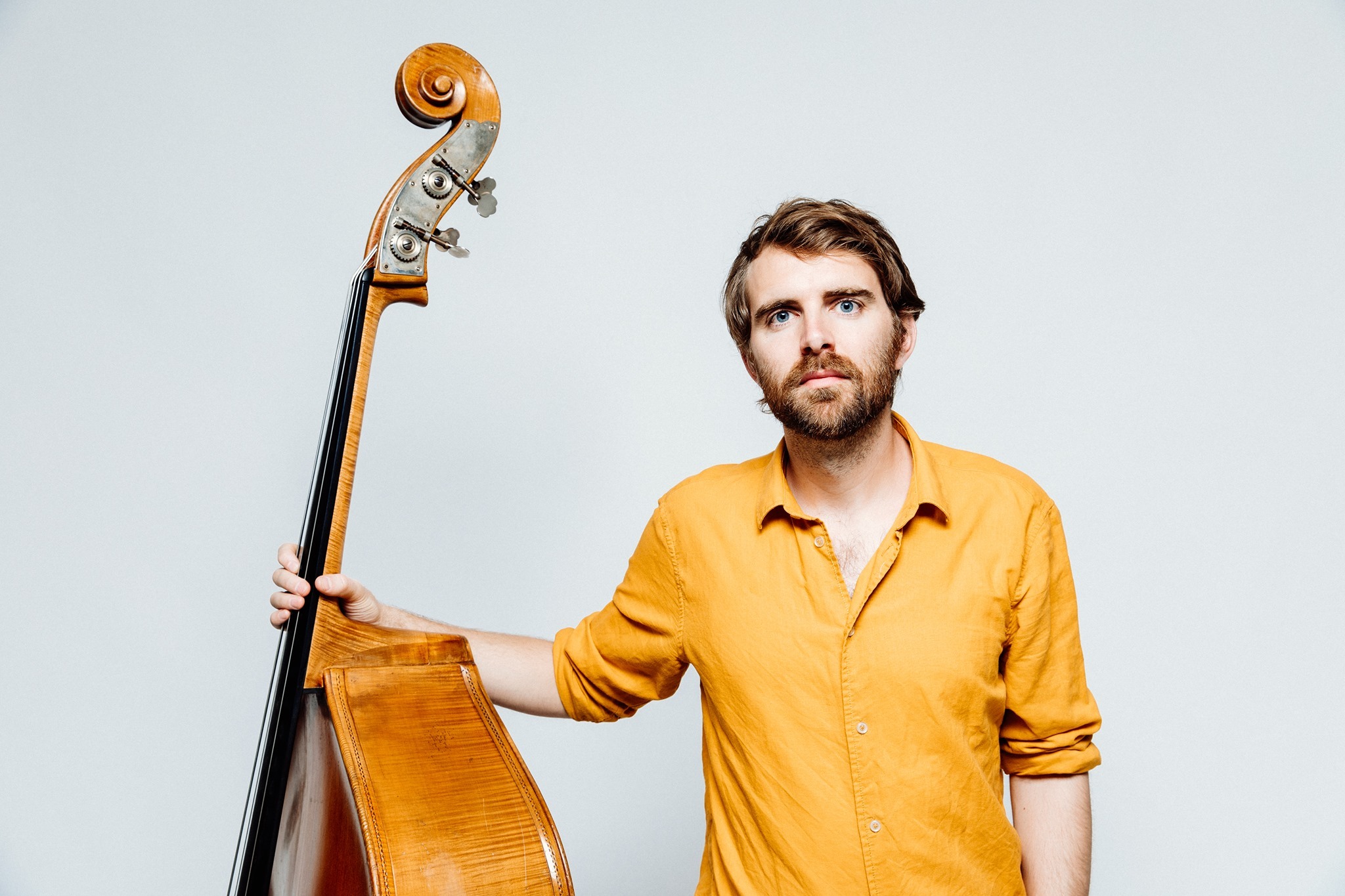 Jo Skaansar står i gul skjorte med kontrabassen sin