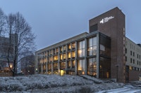 NMH-bygget ligger i et snødekt landskap. Det er mørkt og vinduene lyser.