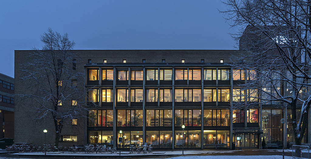 Bilde av fasaden til NMH i halvmørket på vinteren, litt snø på bakken foran.