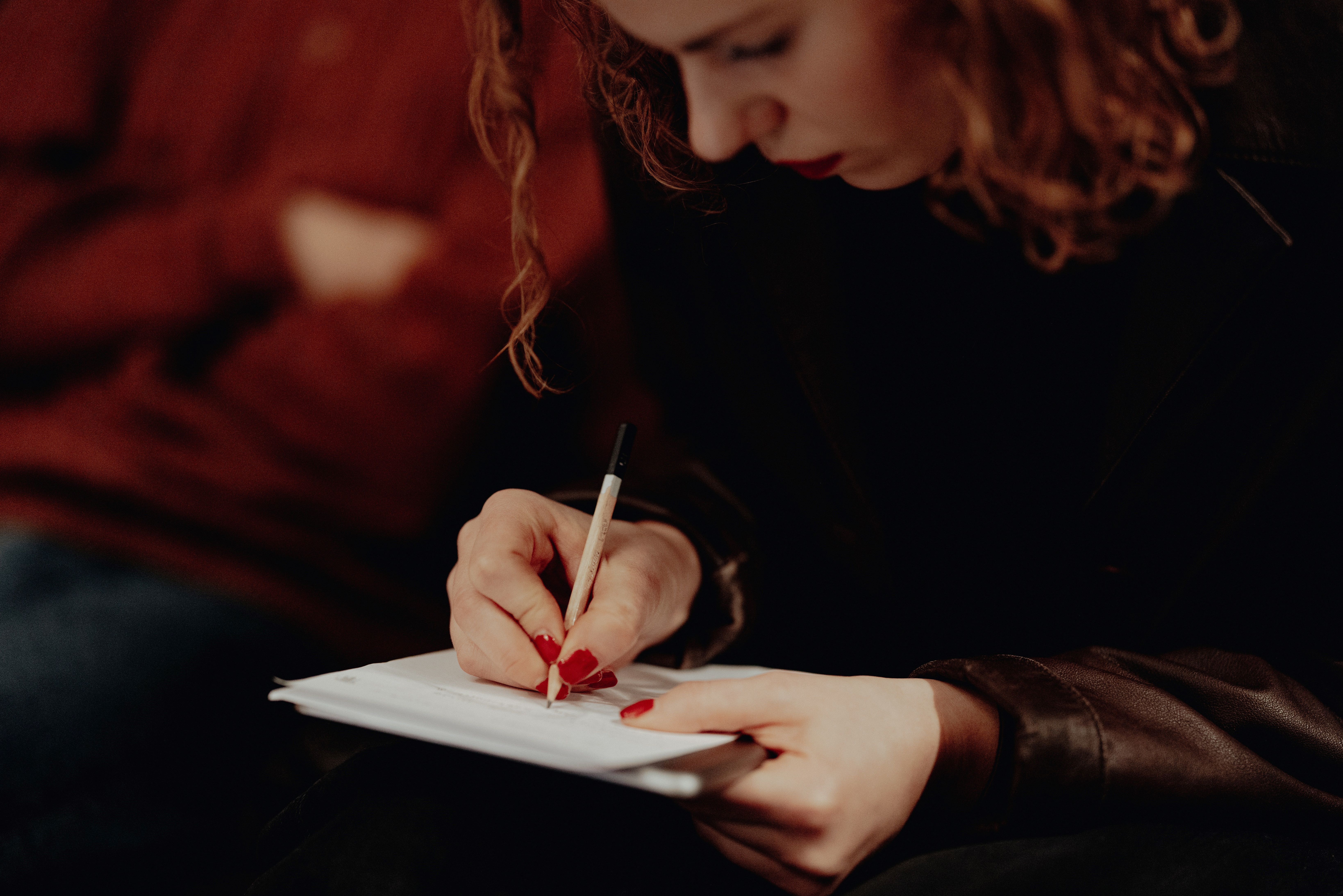 Jente som noterer i blokk med penn