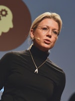 Kvinne med lyst hår og sort genser foran lysende skjerm