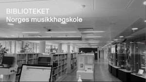 Reoler fulle av bøker og noter, samt utstillingsmontre med historiske instrumenter. Over bildet står det "Biblioteket, Norges musikkhøgskole".