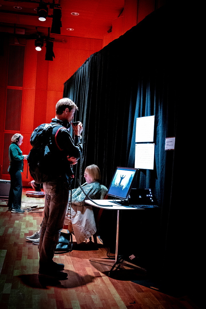 A man with a coffee cup stands in front of a screen exhibit.