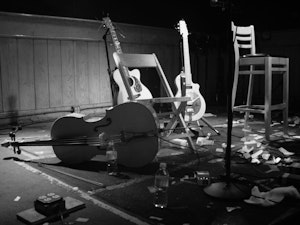 Cello, harpe og gitar står på en scene i svart-hvitt