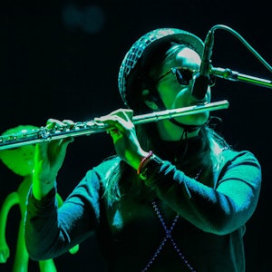 Fløytist med hjelm spiller fløyte i grønt lys på RÅ