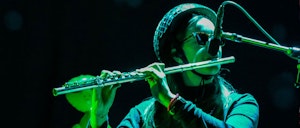 Flutist with helmet plays at Rå! concert series in a mysterious light.