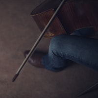 Nærbilde av cello med hender som spiller