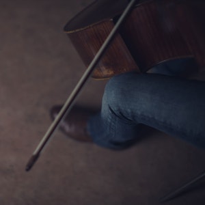 Nærbilde av cello med hender som spiller