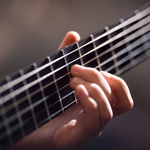Nærbilde av hånd som tar grep på gitar
