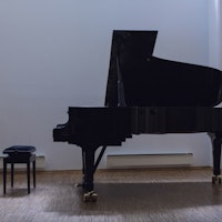 An empty grand piano with a piano stool.
