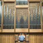 Foran det store orgelet i Lindemansalen sitter en mann og spiller.