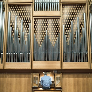 Foran det store orgelet i Lindemansalen sitter en mann og spiller.
