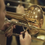 Nærbilde av en skinnende blank trombone som blir spilt på