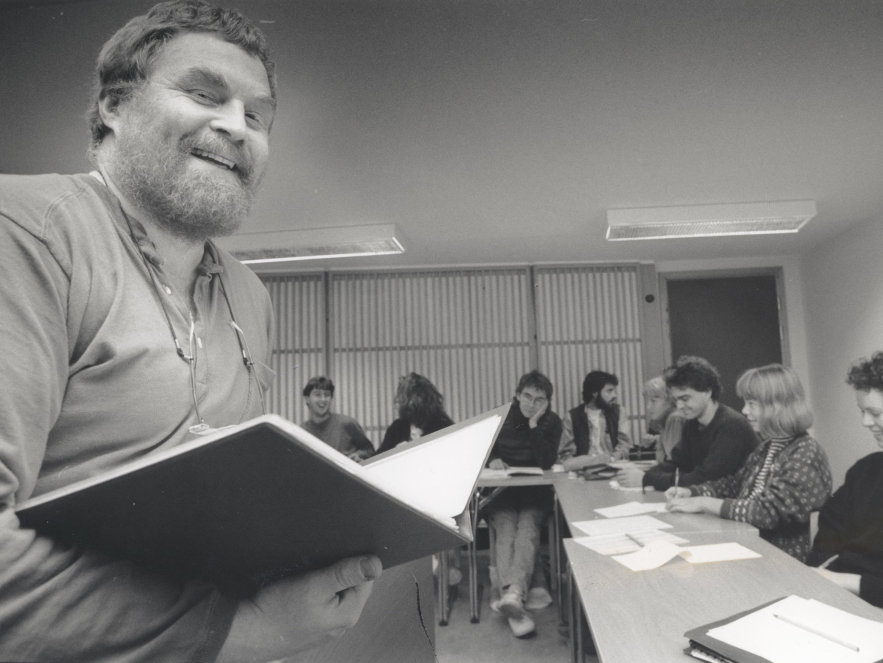 En smilende Olav Anton Thommesen foran studenter som sitter i hestesko i undervisningsrommet.