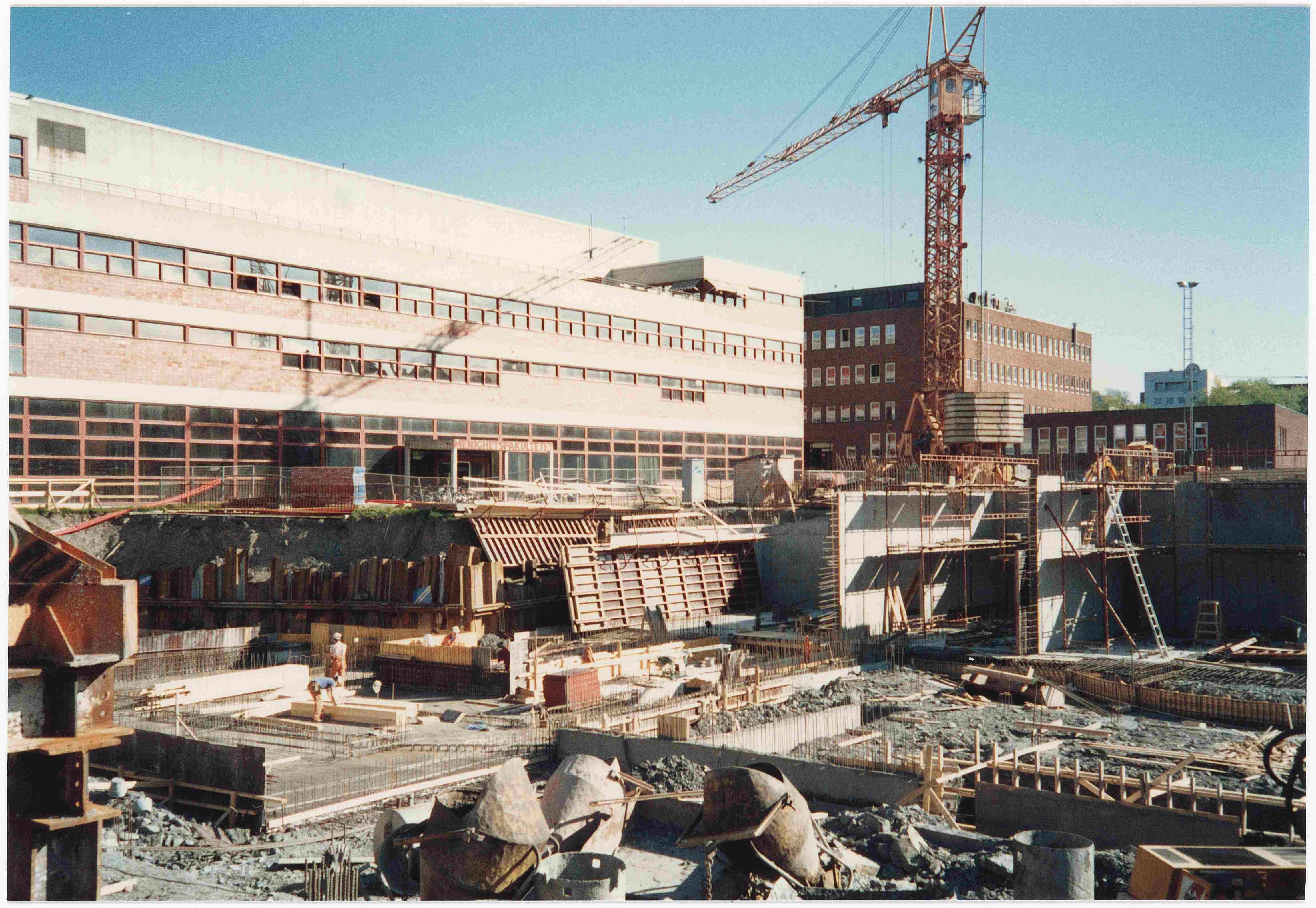 Byggetomt med kraner, grunnmur og materialer.