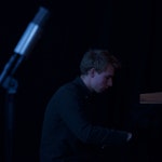 Øystein Folkedal sitter spiller piano i mørket.