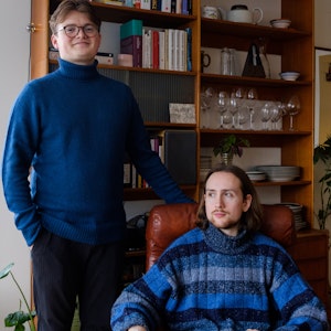 Sigmund Toppe står foran en bokhylle, mens Jon Svenungsson sitter i en brun lenestol.