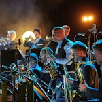 Konsertbilde av Bohuslän Big Band i mørk konsertsal med lys i bakgrunnen.