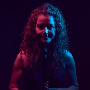 Mørkt bilde med lilla lys, av Daniela Braun med klarinett.