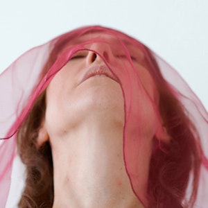 Elisabeth Holmertz bøyer hodet bakover med rødt sjal over ansiktet
