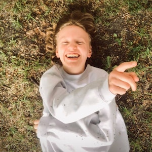 Hanna Kallestad ligger og ler i gresset og peker oppover.