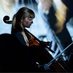Inga Grytås Byrkjeland med cello på konsert foran storskjerm.