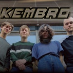 Bandet Kembro foran et vindu, med store, tykke bokstaver over med «KEMBRO».