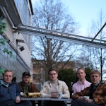 Medlemmene i bandet Lyng sitter ved et bord foran Musikkhøgskolen