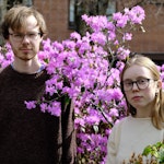 Maren Sofie Nyland Johansen og Eivind Holmboe Leifsen står foran en busk med rosa blomster.