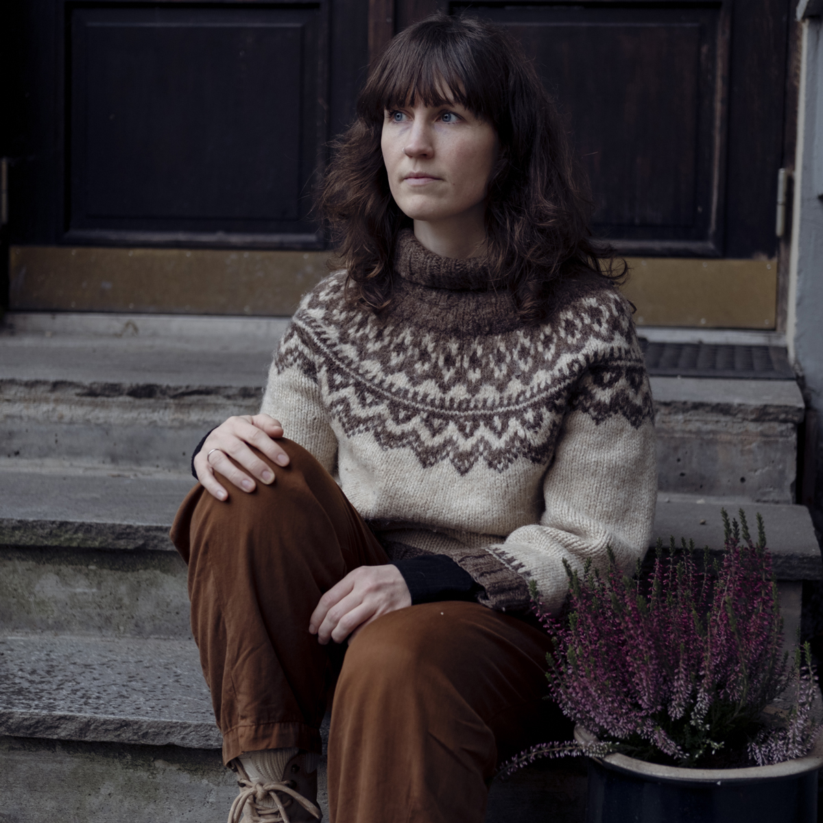 Runa Kvalsund sitter i kofte på en steintrapp og ser utover.