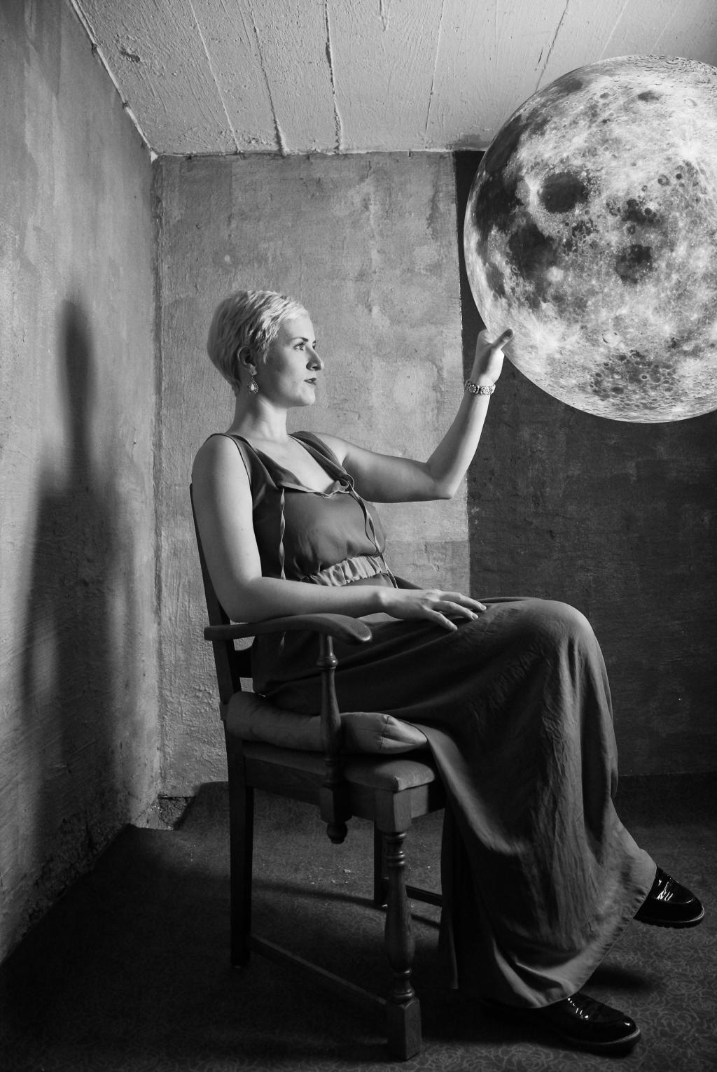 Sophia Körber sitter i et rom og holder hånden på en stor planet eller måne som henger foran henne.