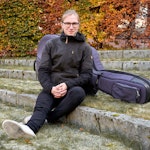 Sverker Rundqvist sitter på en steintrapp med kontrabassen ved siden av seg.