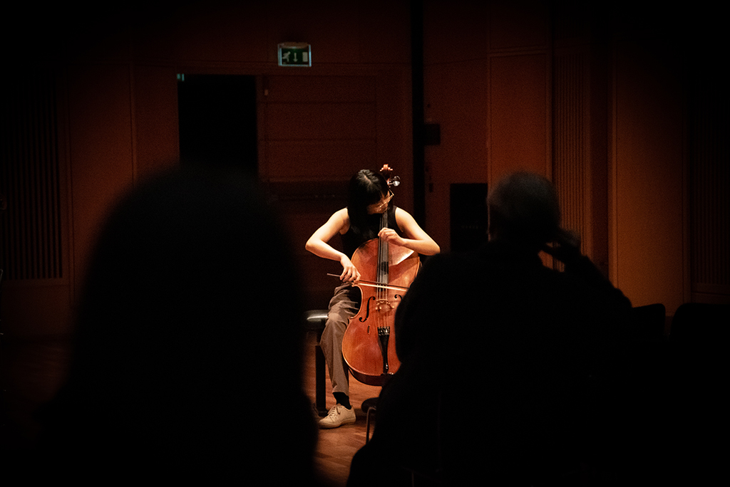 Cellist on a dark stage in Lindemansalen. Wei Ting Tseng playing solo cello.