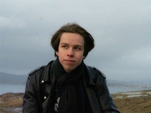 William Dillner ser til siden og sitter foran fjordlandskap.