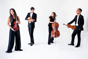 Musikerne i Zorá Quartet står med instrumenter i et helt hvitt rom.