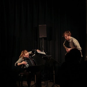 Eivind Holmboe Leifsen og Maren Sofie Nyland Johansen spiller konsert i veldig mørkt rom.