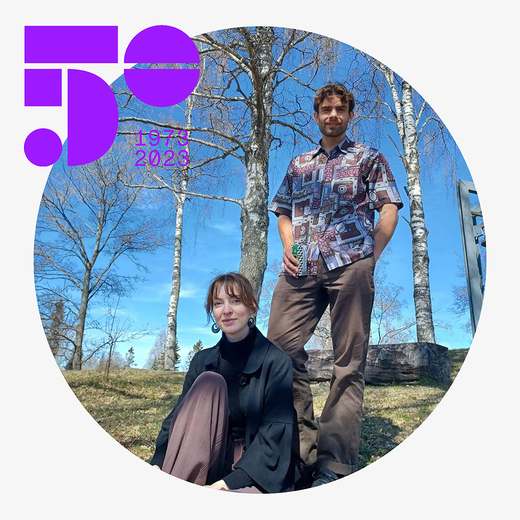 Morten Strøm står bak Marta Bøshaugen som sitter i en bjørkeskog med blå himmel.