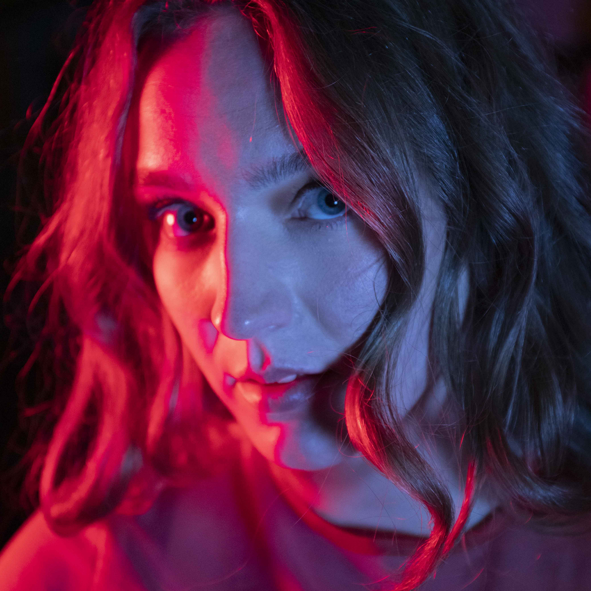 Portrett av Elise Sløgedal i rød og lilla farger og lys.