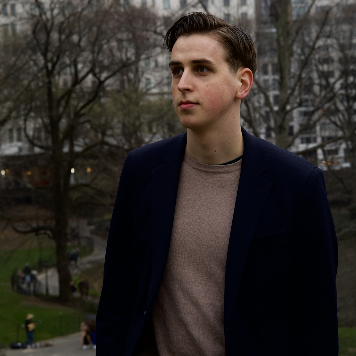 Potrett av Henrik Bålerud Haugen som står i en høstlig park med bygg i bakgrunnen.