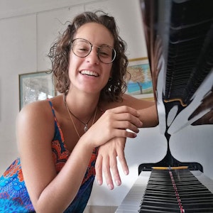 Jelena Ilic sitter ved klaveret og smiler bredt.