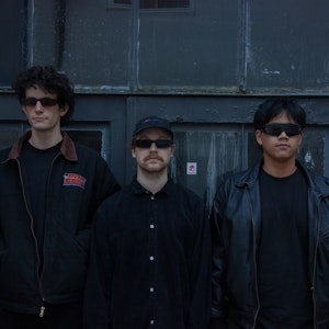 Medlemmene i bandet Karbon står foran mørkeblå vegg, med solbriller og ser alvorlige ut.