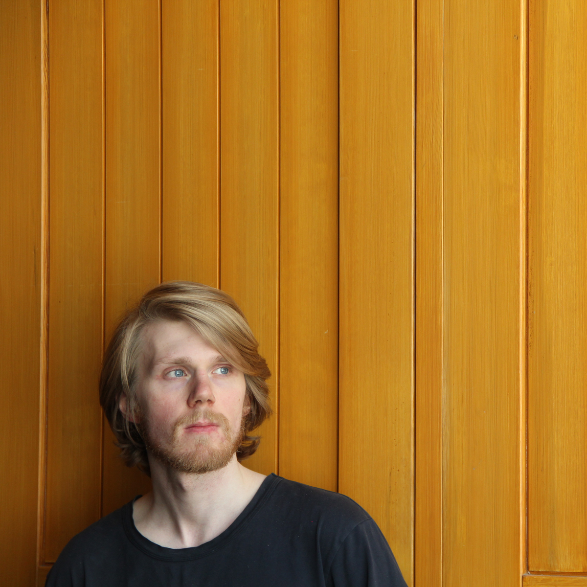 Portrett av Olaf Andreas Strand foran gul vegg.